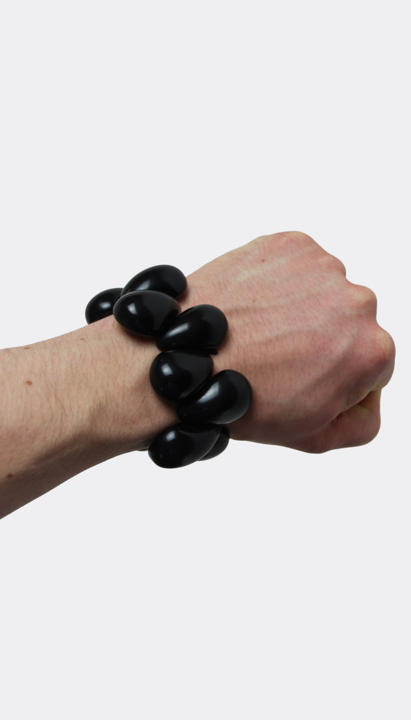 Hand wearing a black tagua nut bracelet on a white background