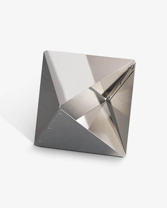 A modern geometric metal side table with a silver finish, photographed on a clean light grey background.