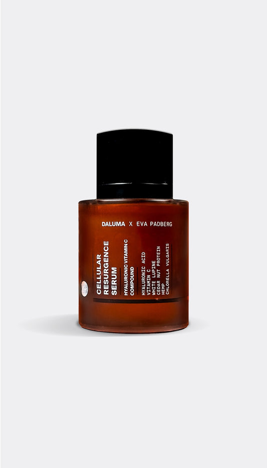 A bottle of Daluma Cellular Resurgance Serum with a dark liquid visible through the clear glass container and a black cap.