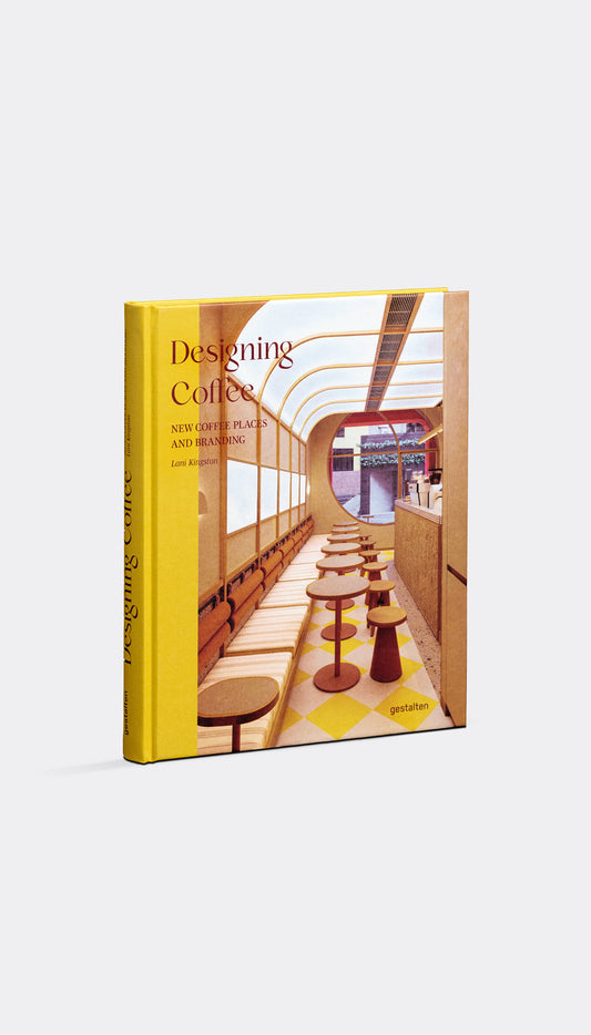 A book titled 'Designing Coffee' with a yellow cover featuring an image of a coffee shop with wooden furniture and a modern design.