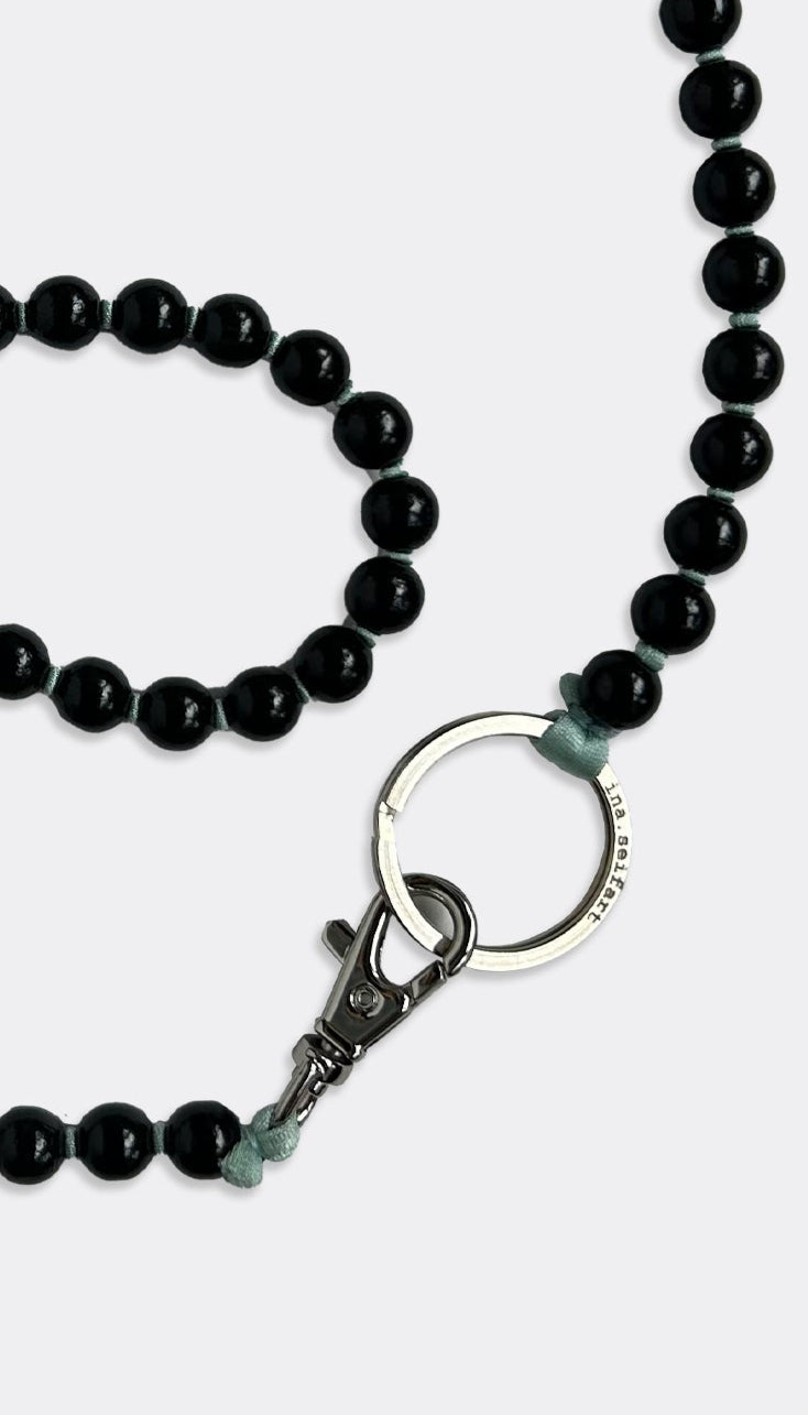 A black fabric band keychain with elegant painted wooden beads and a polished silver ring.
