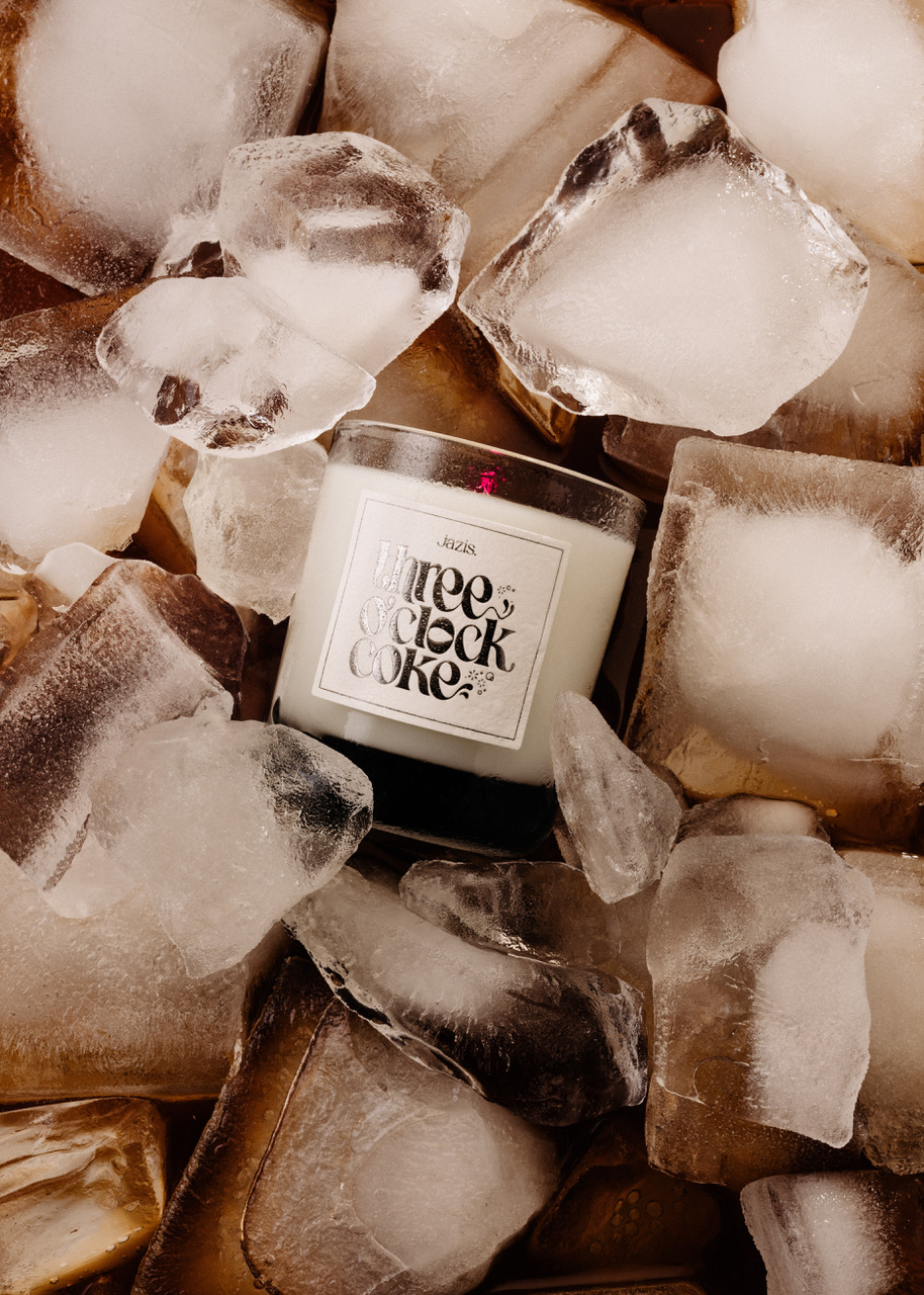 Candle labeled 'Three O'Clock Coke' surrounded by ice cubes