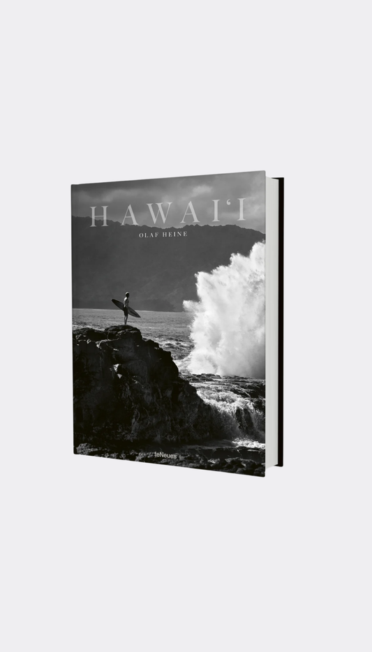 Book cover with a black and white photo of a surfer on rocks and crashing waves, with 'Hawaii' text by Olaf Heine