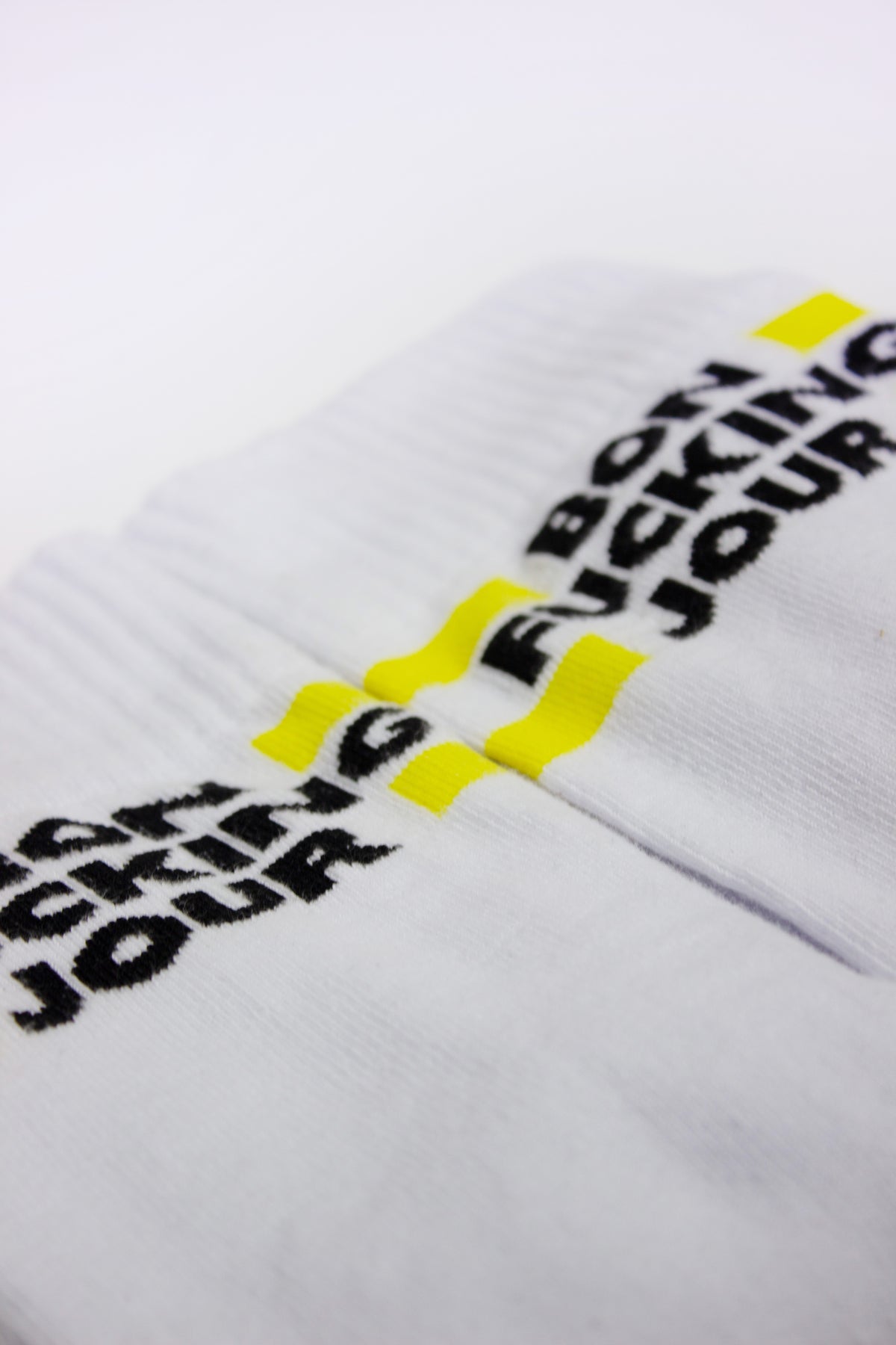 White SUPERMARQUE socks with black text and yellow accents on a white background