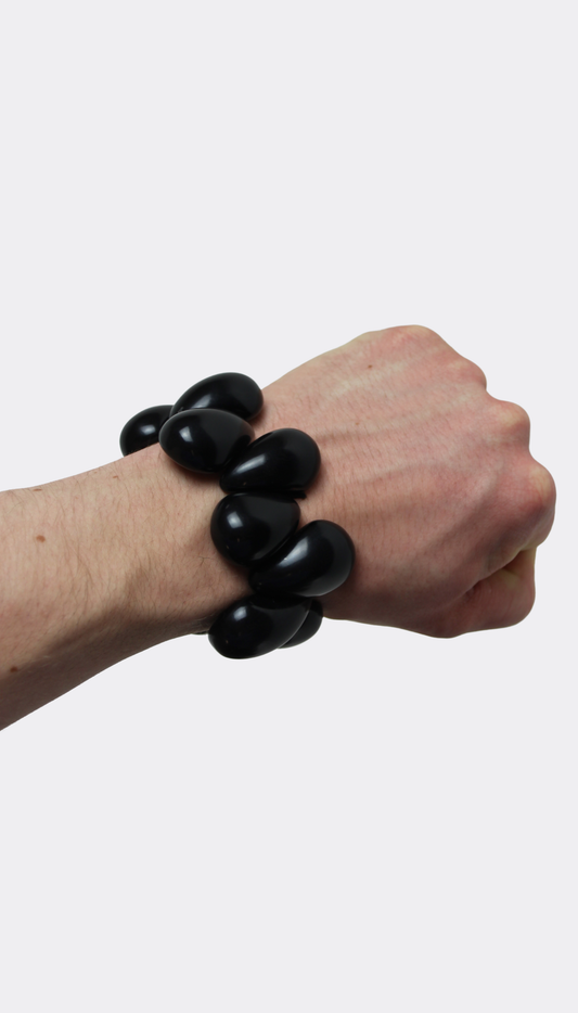 Hand wearing a black tagua nut bracelet on a white background
