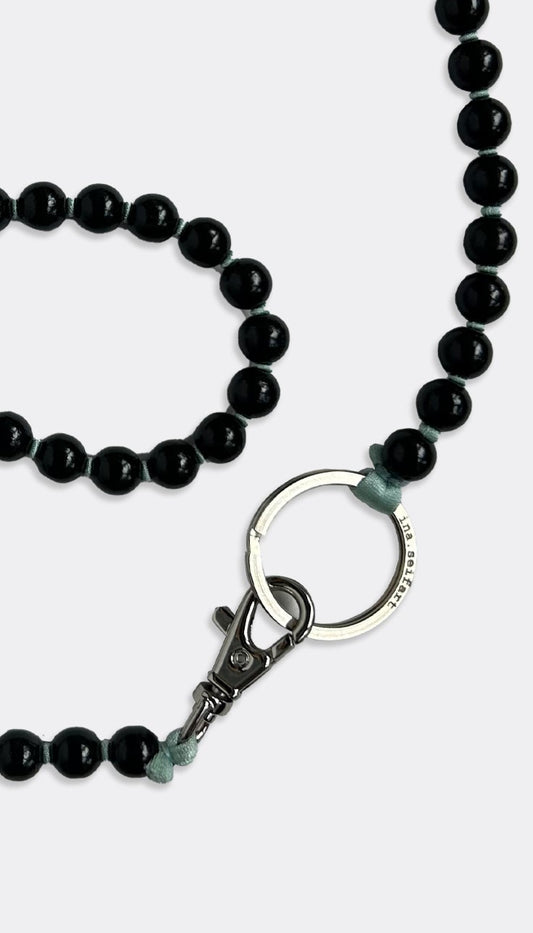 A black fabric band keychain with elegant painted wooden beads and a polished silver ring.