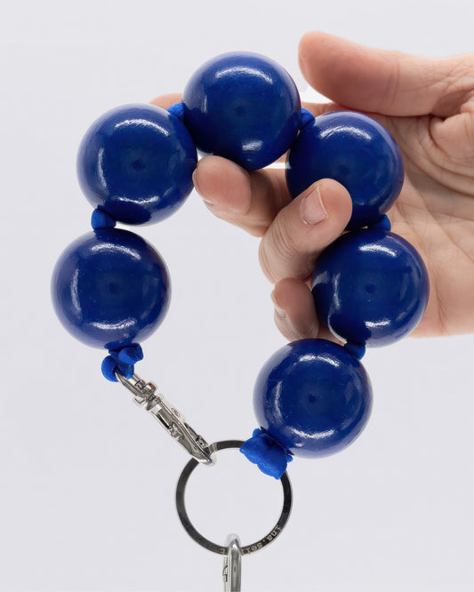 Hand holding a blue beaded keychain against a white background