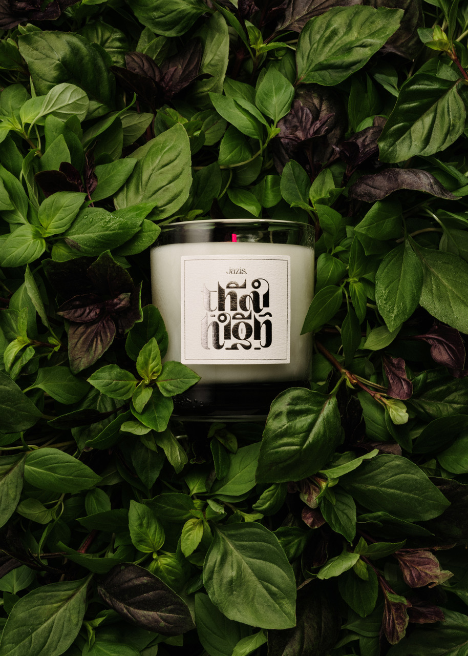 Thai High Candle with a white label surrounded by green leaves