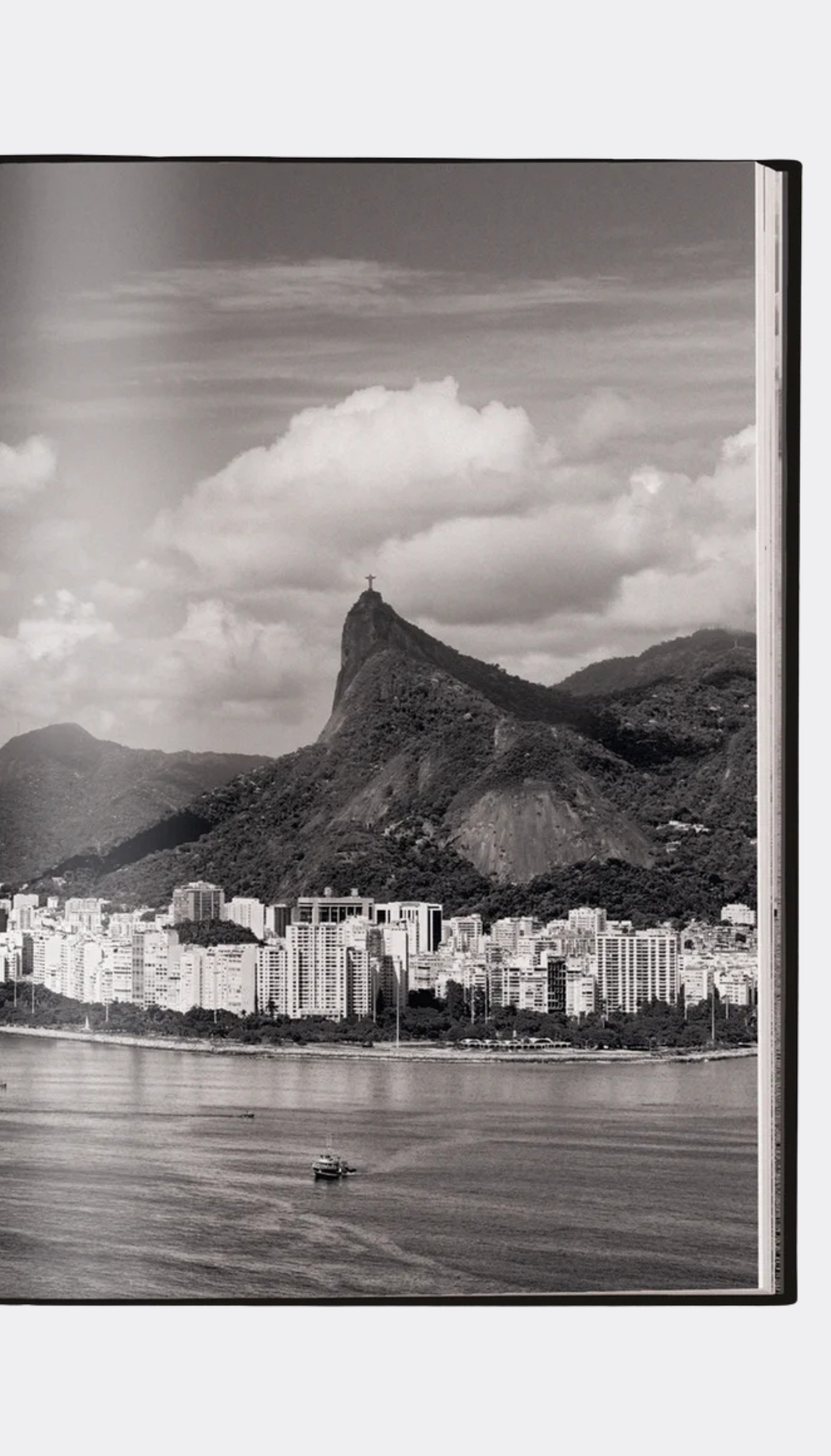 Black and white photo of a cityscape with mountains and a body of water.