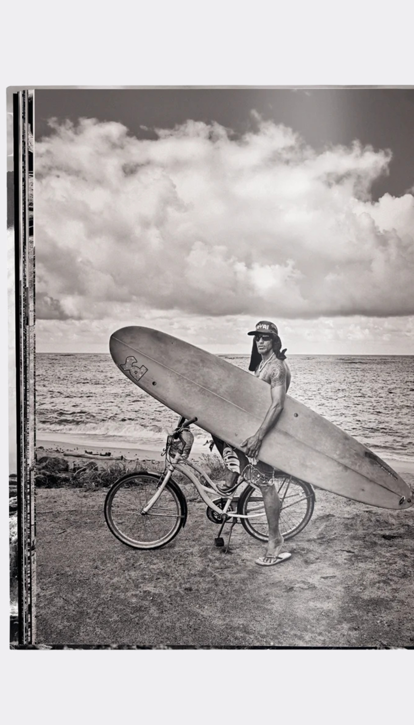 Person with a surfboard and bicycle on a beach