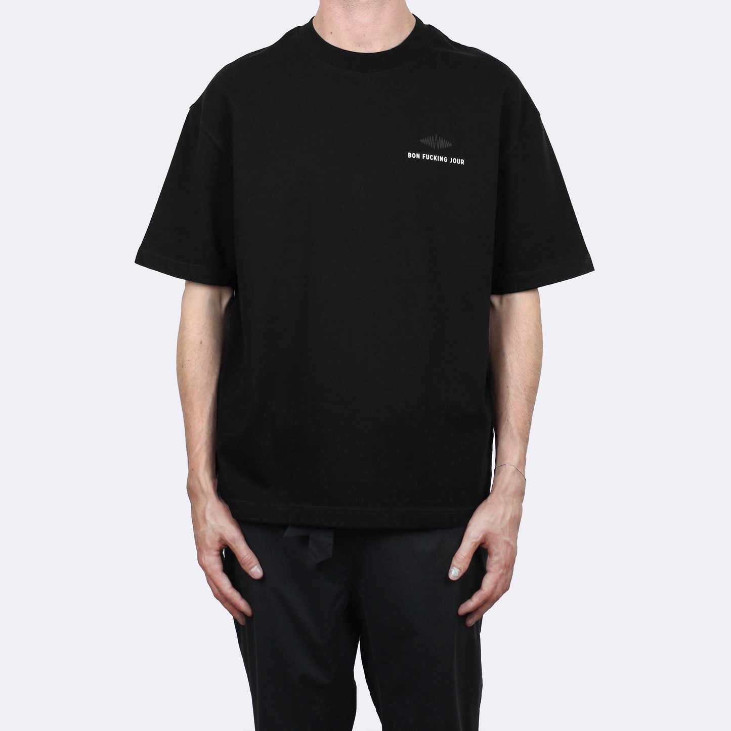 Person wearing a black t-shirt with a small print on a white background