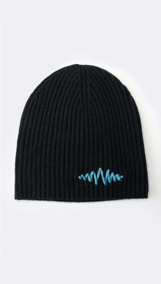 A black ribbed cashmere beanie with a signature logo hand-embroidered in blue on the front.