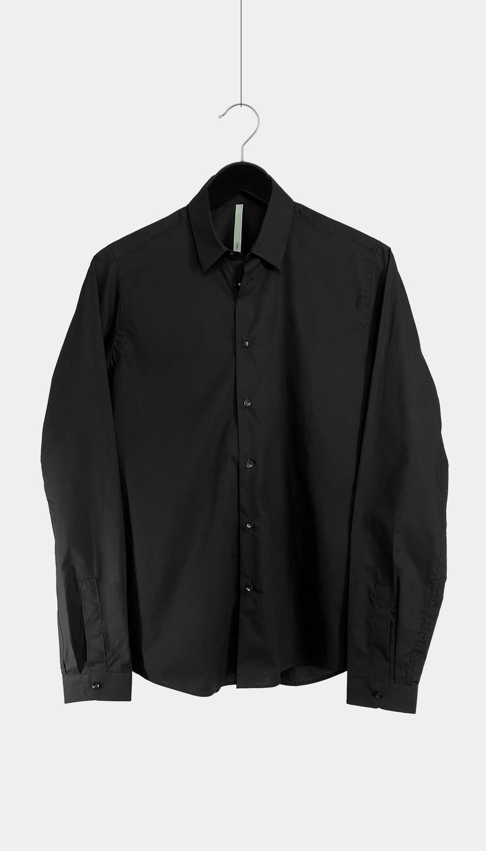 A black cotton poplin shirt with a point collar and buttoned cuffs, hanging against a white background.