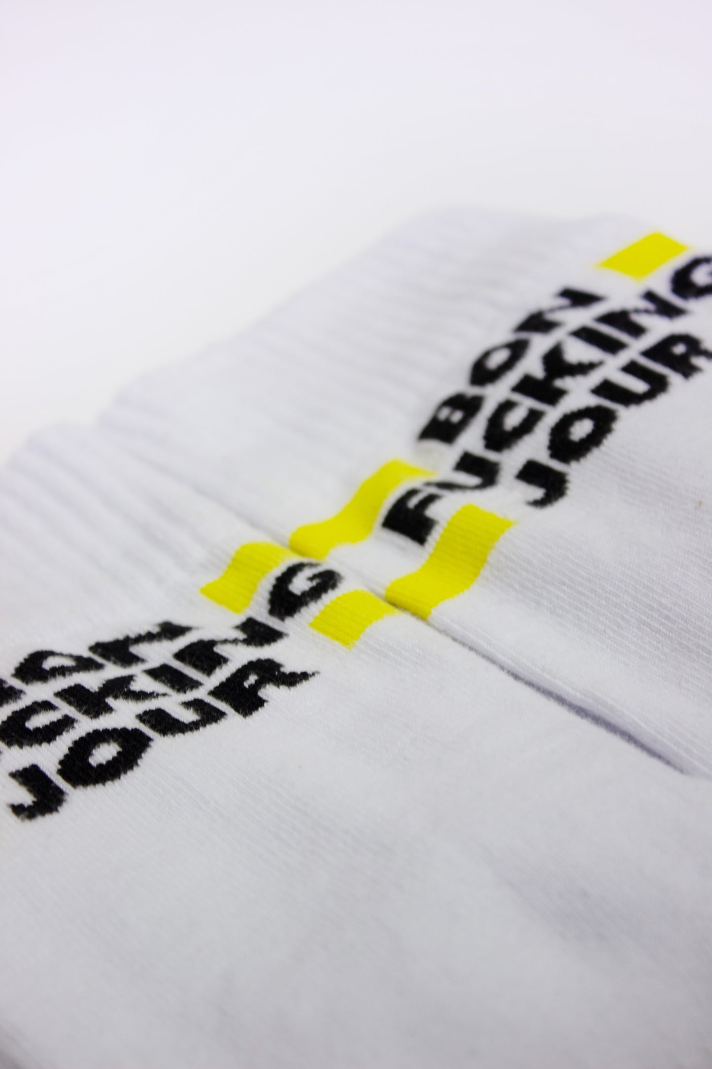 White SUPERMARQUE socks with black text and yellow accents on a white background
