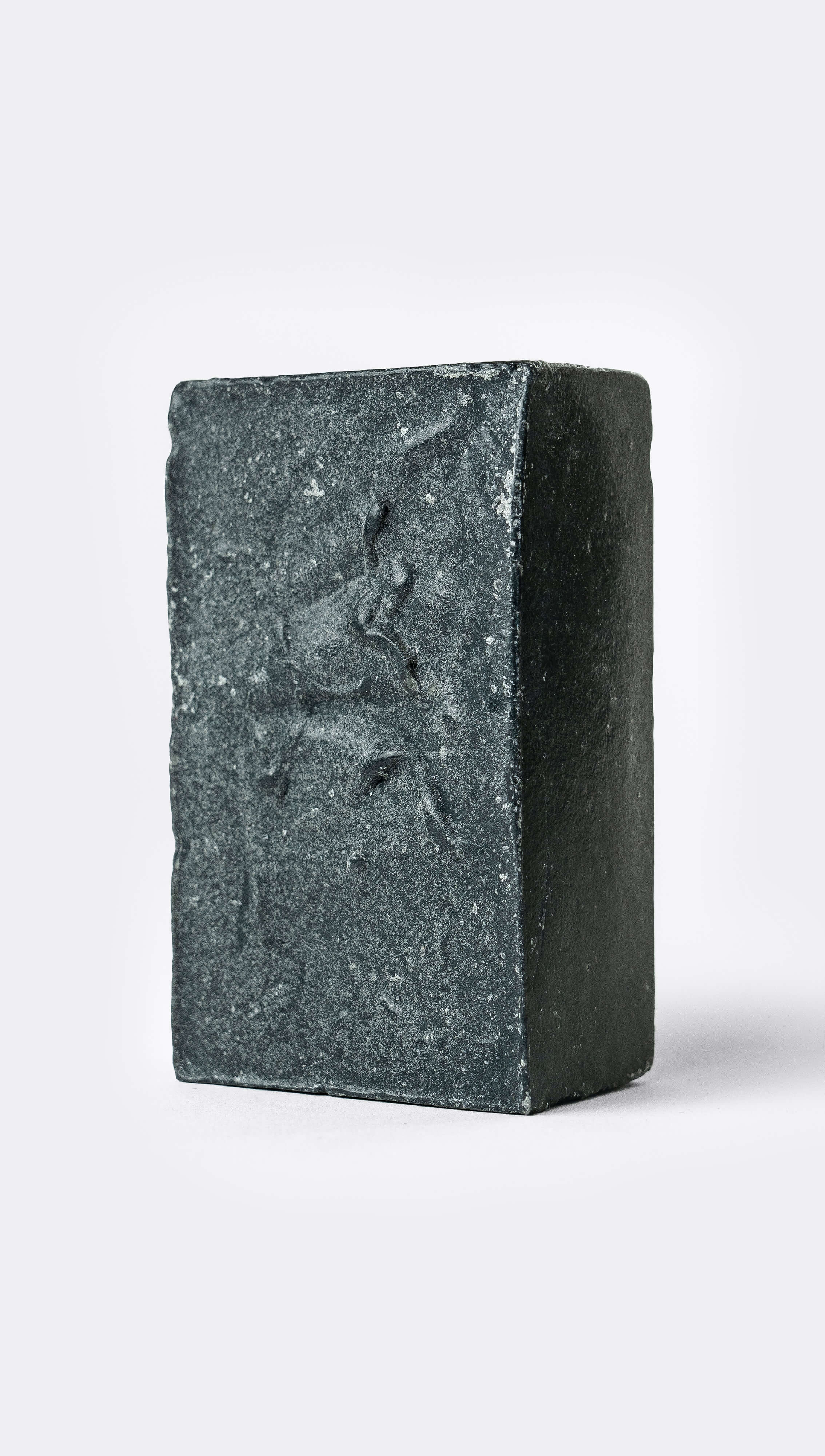 A bar of organic soap with a textured, black surface