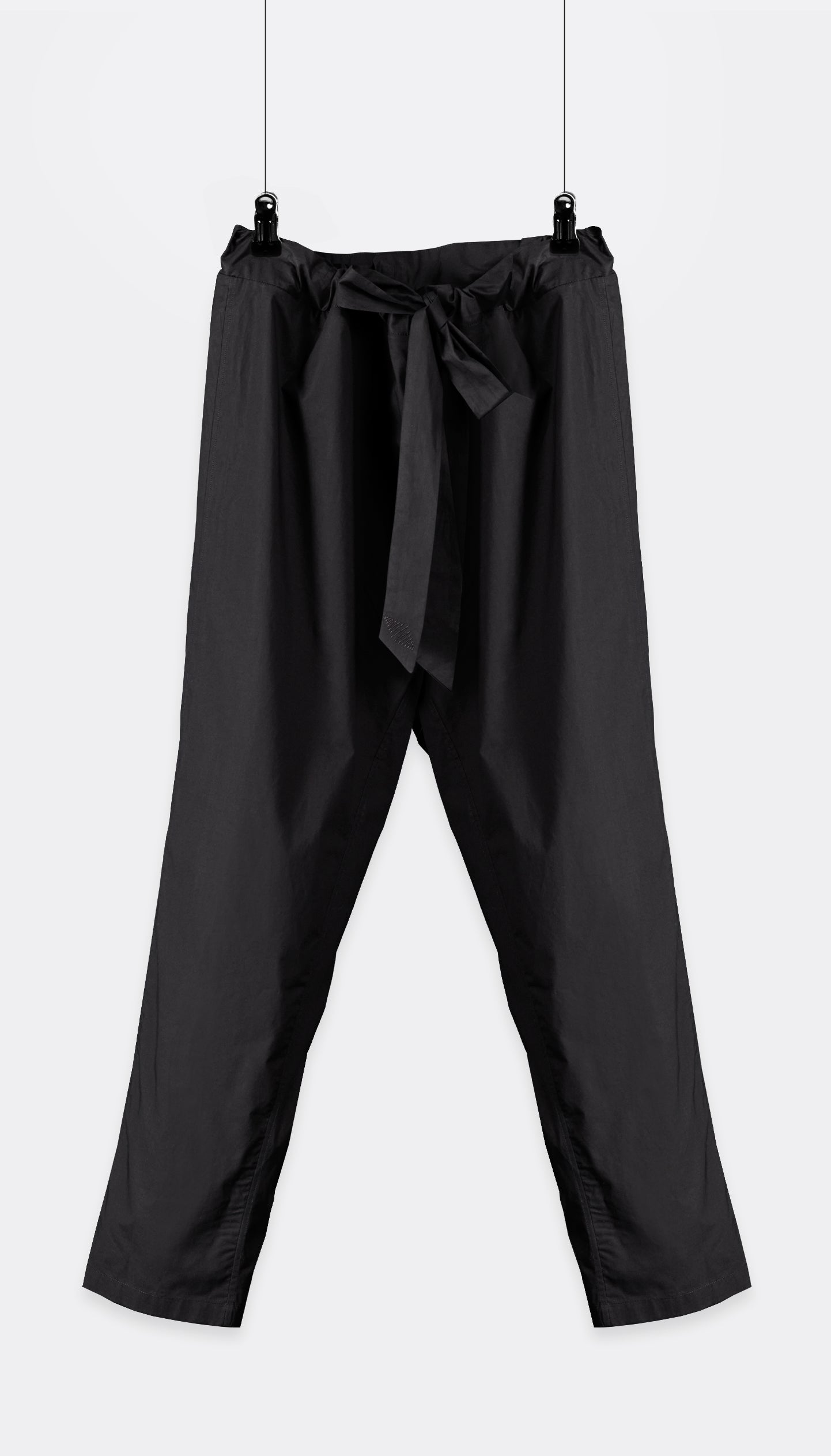 A pair of Outama pants with an integrated belt, hanging against a white background.