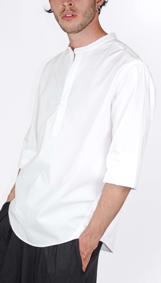 Man wearing a white SUPERMARQUE Outama shirt and black pants on a white background