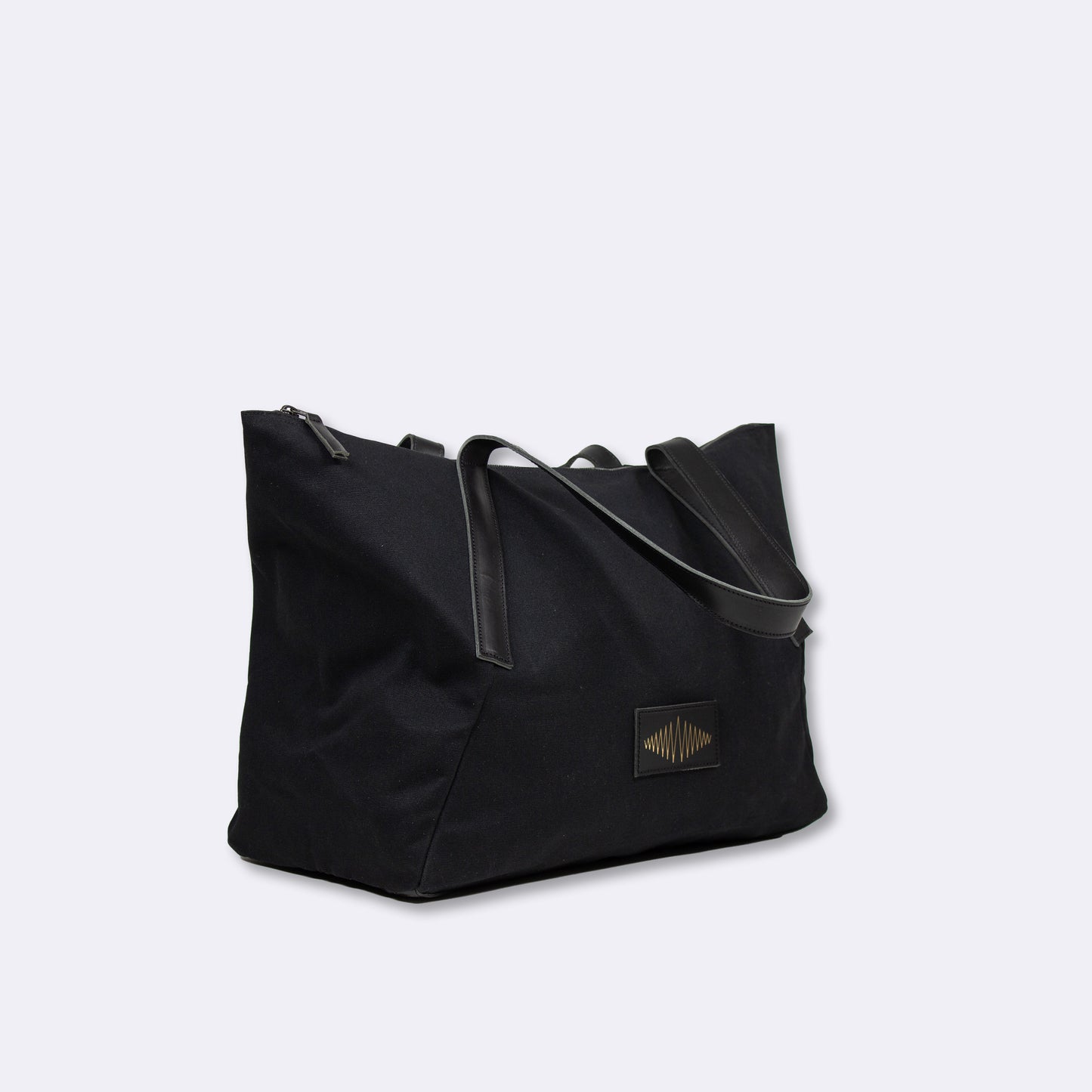 Black everyday weekender bag with a visible gold brand logo on a light gray background